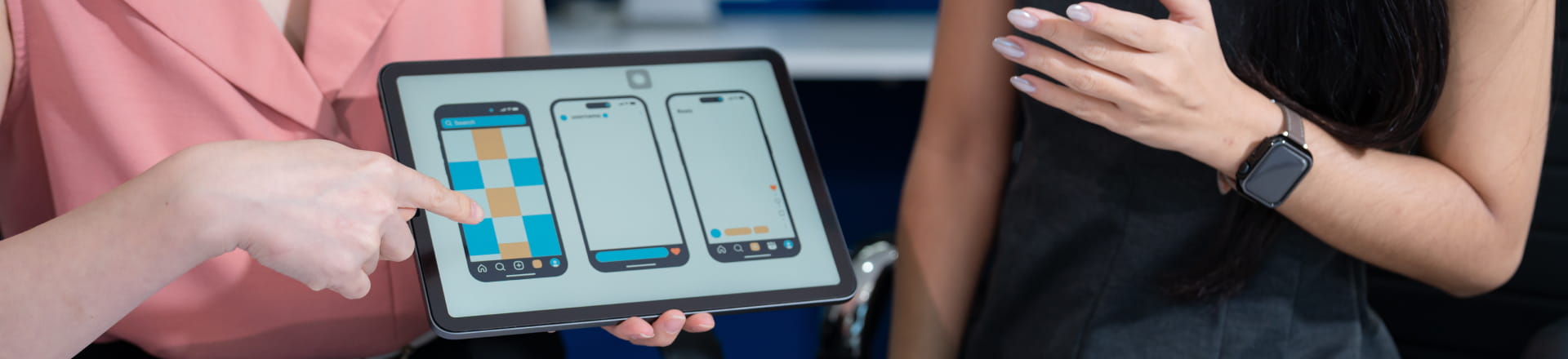 タブレットに表示したアプリのワイヤーフレームを指差しながら2人でデザインを確認している様子